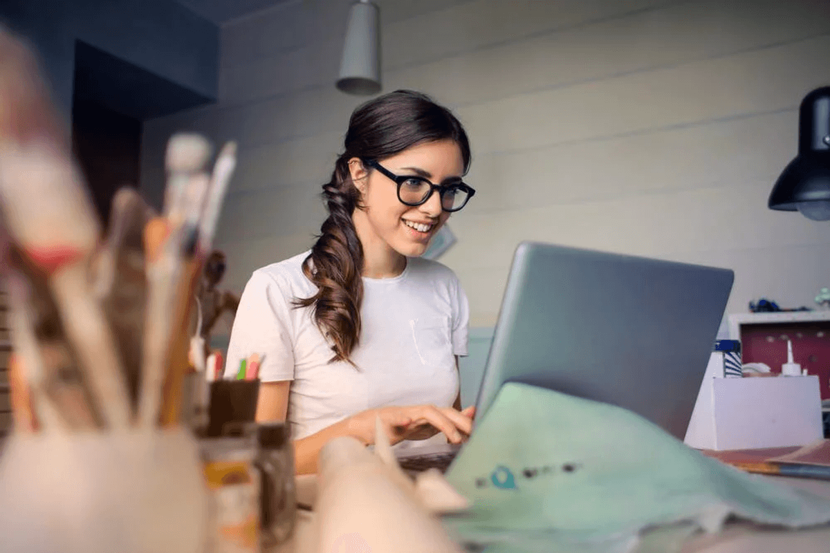 girl on laptop with paintbrushes