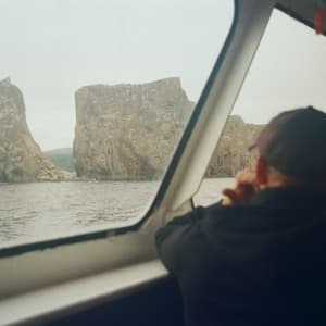 Man staring outside of boat at mountain